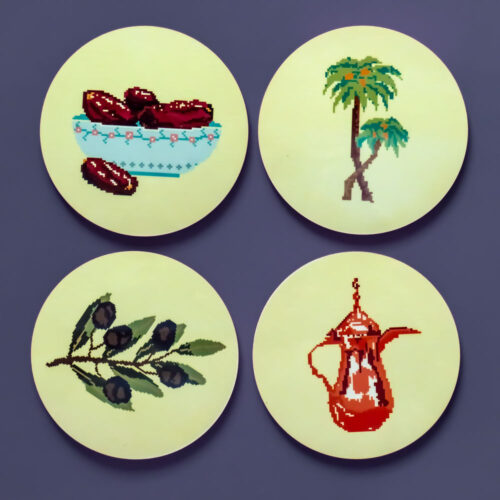 A set of four circular MDF coasters featuring illustrations of a palm tree, olive branch, Dallah, and a bowl of dates on yellow backgrounds.